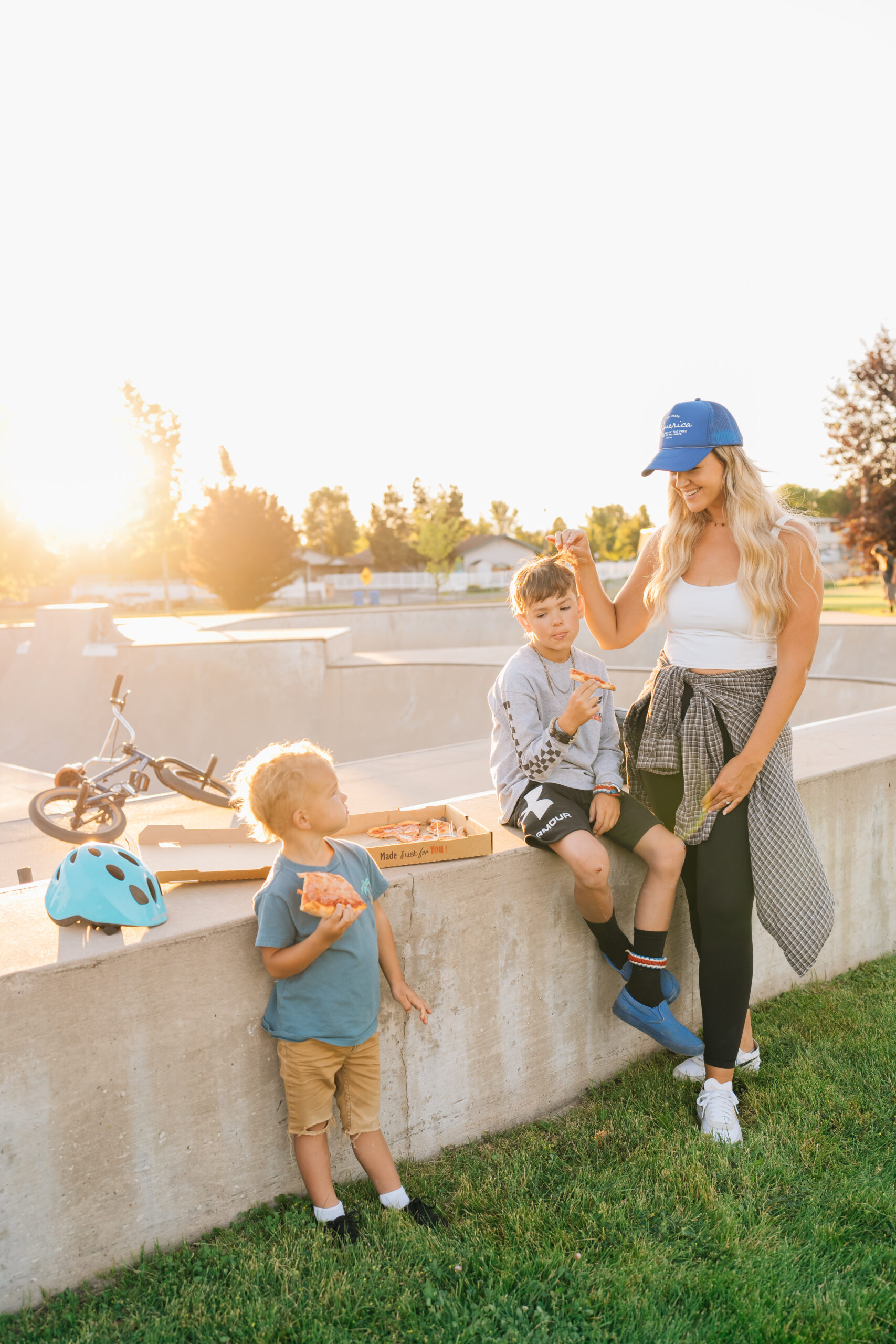 a woman and two boys sitting on a concrete ledge